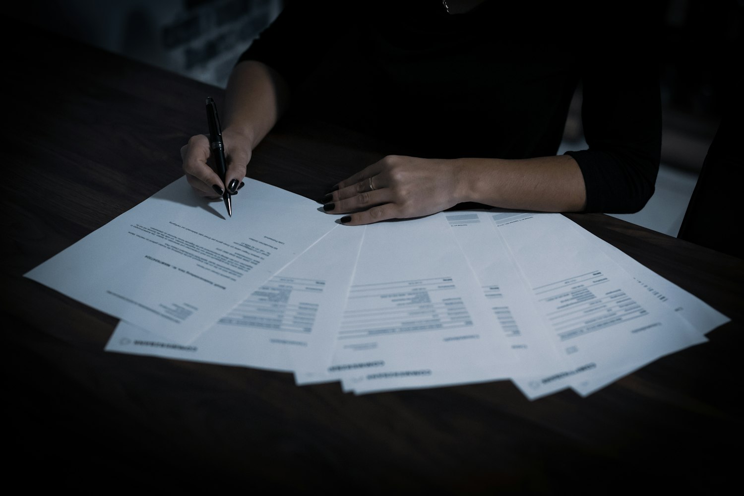 An analyst working through a spread of documents by hand